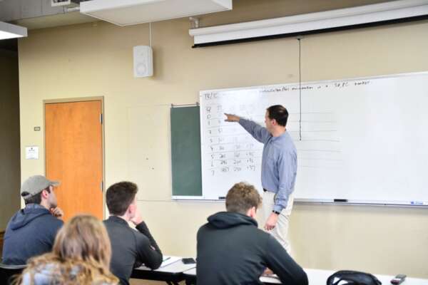 High school students listen to the instructor during Economics class in BCYC Immersion