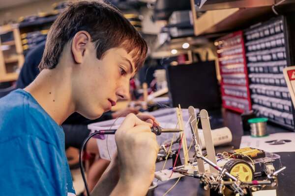Student soldering wires to make a robot