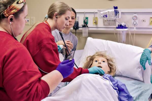 Nursing students assessing a mannequin's health