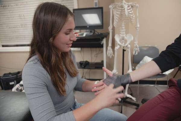 student learning to wrap an injured wrist