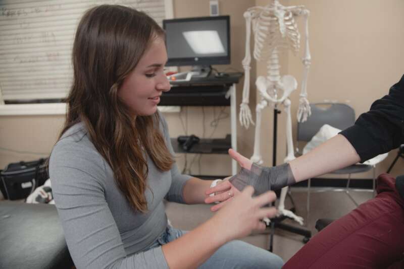 student learning to wrap an injured wrist