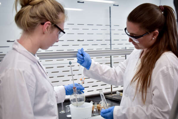students working in a labcoats for a chemistry project