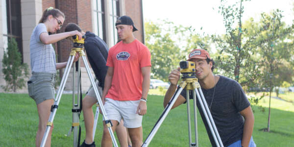 Several students looking through tripod cameras