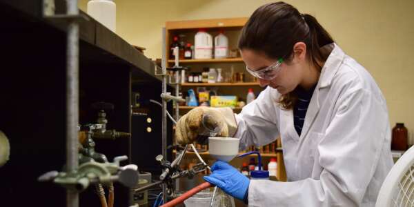Student pouring solution from a beaker into a funnel