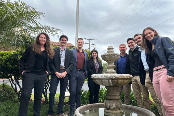 Students and professors in business casual outside with palm trees