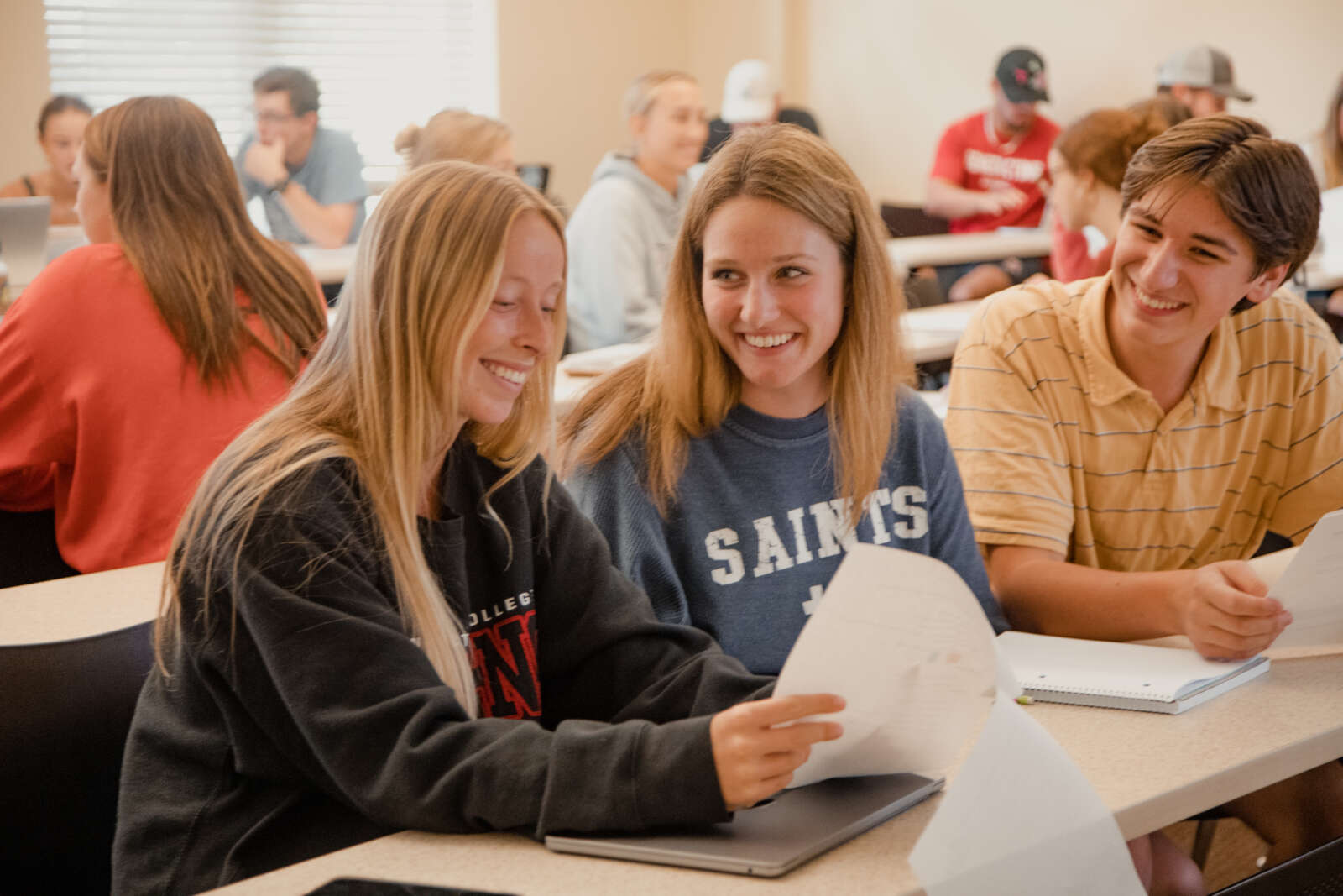 Students smiling looking at notes and assignment