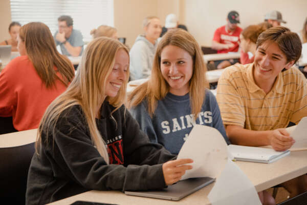 Students smiling looking at notes and assignment