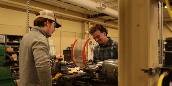Two students working with machinery wearing safety goggles
