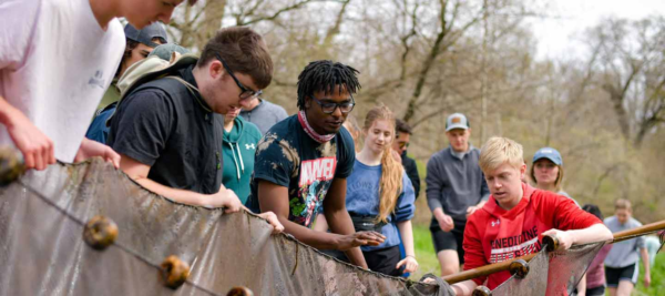 Students work with netting in a stream