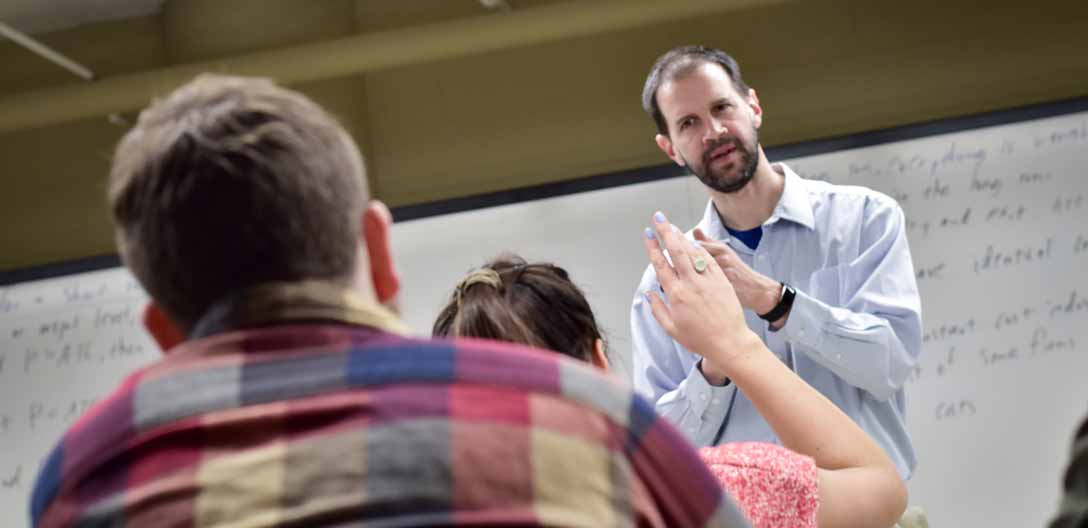 A student raises her hand to ask a question in class