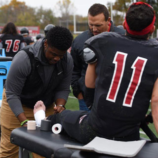 A student binds a football player's foot