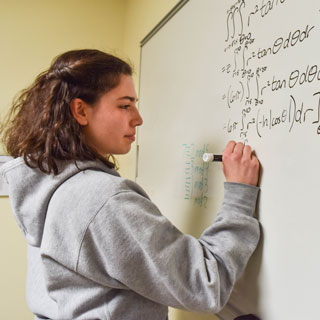 Student writing equations on the board
