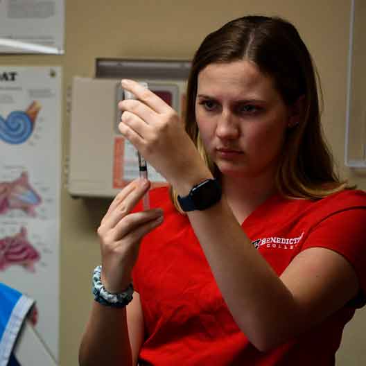 A nursing student fills a syringe