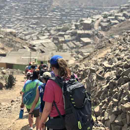 Students descend a hill to a refugee camp